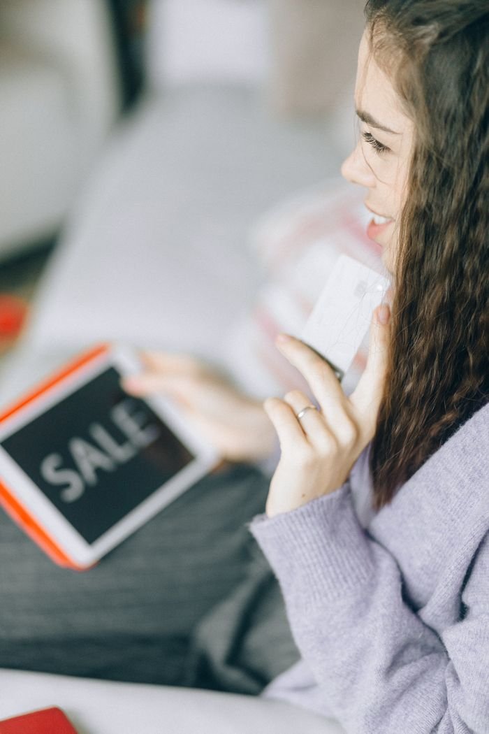 Home Woman holding a credit card and tablet with Sale for online shopping.