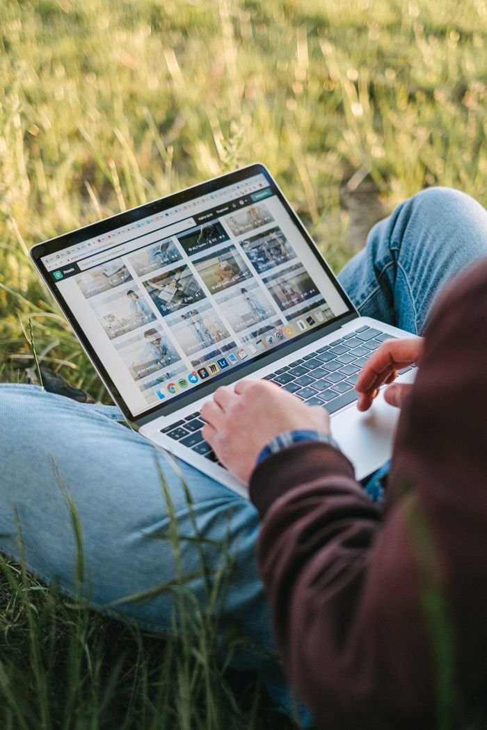 Home A person working remotely on a laptop while sitting on the grass outdoors, showcasing a digital lifestyle.